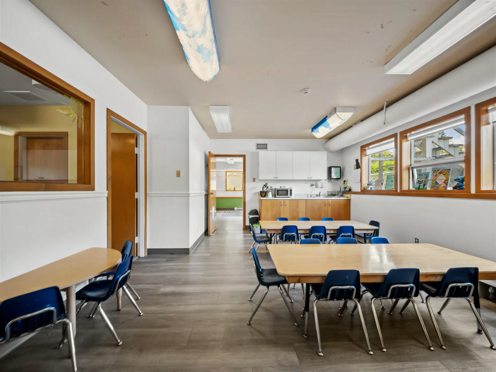 The Blooms Room with wooden tables, blue chairs and a wall of windows