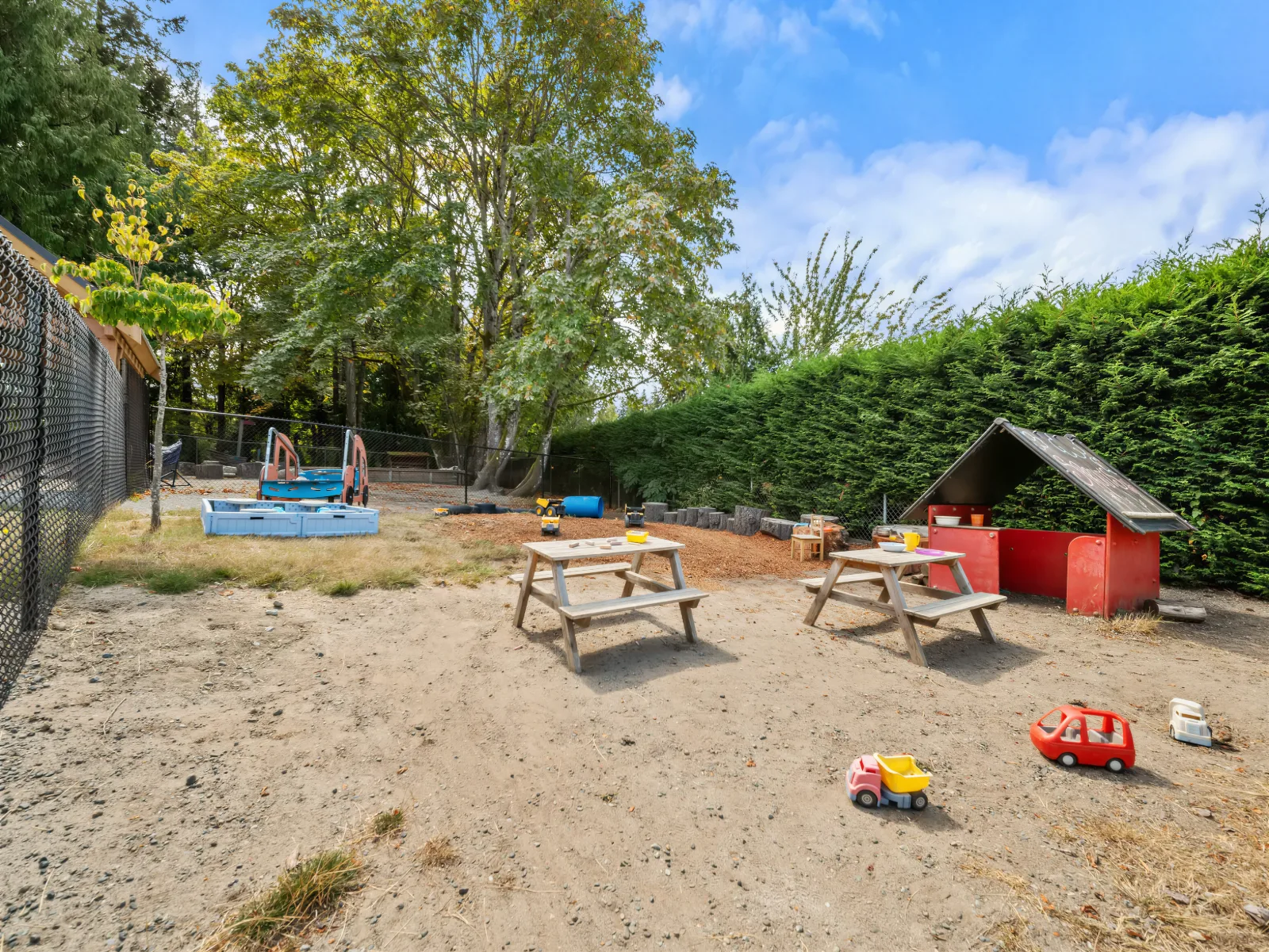 Outdoor yard with picnic tables, sandbox and a red mud kitchen